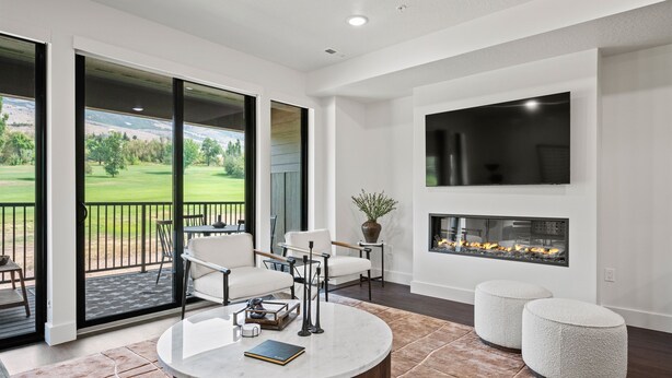 A modern living room with a fireplace, comfortable seating, and a large window overlooking a green landscape. - Alpine Adventure Pt C201 | Ski Escape | Powder Mtn (Eden)