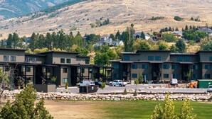 A modern building with multiple units, a parking area, and a mountainous backdrop. - Alpine Adventure Pt C201 | Ski Escape | Powder Mtn (Eden)