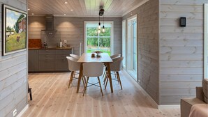 A modern kitchen with wooden cabinets and a dining area with a table and chairs. - 4 bedroom nice home in Hildre (Hildre)