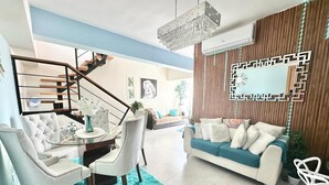 A modern living room with a staircase, white furniture, and a decorative wall panel. - Luxury Penthouse DGM Resort at Boca Chica  (Boca Chica)