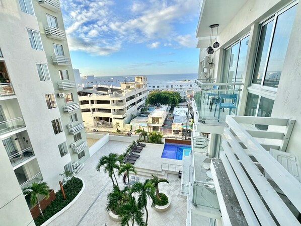 A high-rise building with a rooftop pool, multiple balconies, and a view of the sea.