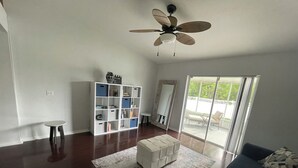 A spacious living room with a ceiling fan, a white bookshelf, a round coffee table, and a dark-colored sofa. - Tampa Bay Large Vacation Home (Ruskin)