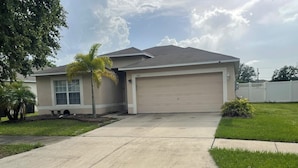 A single-story house with a garage, a front lawn, and a palm tree. - Tampa Bay Large Vacation Home (Ruskin)