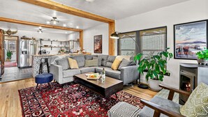 A spacious living room with a gray sectional sofa, a wooden coffee table, and a red patterned rug.