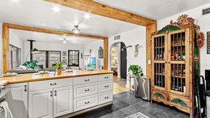 A spacious kitchen with a large island, white cabinetry, and a wooden ceiling.