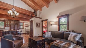 Un salón espacioso con chimenea, una zona de comedor con armarios de madera y un ventanal con vistas al exterior.