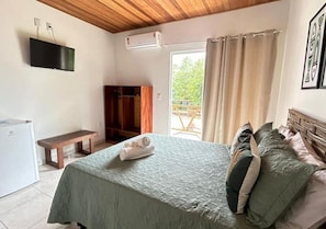 A bedroom with a bed, a bench, a wardrobe, and a television.