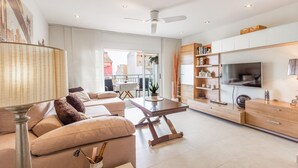 A modern living room with a sofa, coffee table, TV, and bookshelf.