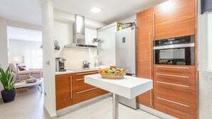 A modern kitchen with white countertops, wooden cabinets, and stainless steel appliances.