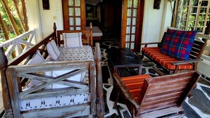 A traditional wooden interior with a stone floor, a wooden bench with a cushion, and a table with chairs. - Sophia Baharini Diani Apartments (Diani Beach)