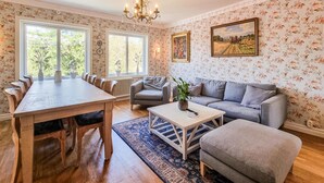 A living room with a wooden dining table, grey sofas, and a chandelier.