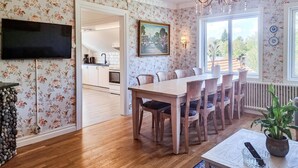 A dining area with a wooden table and chairs, a chandelier, and a view of the kitchen through an open doorway.