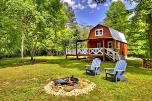 A red cabin with a porch and two Adirondack chairs in a grassy yard. - Ocoee Cottage | Water Front (Copperhill)