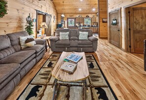A cozy cabin interior with a sofa, armchair, and a coffee table with a book.