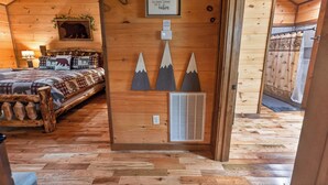 A cozy cabin interior with a bed, a wall-mounted bear silhouette, and a framed inspirational quote. - Squirrels Hideaway | Fire Pit | MTN Views (Copperhill)
