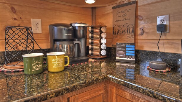 A kitchen with a coffee maker, kettles, and a coffee grinder on the counter.