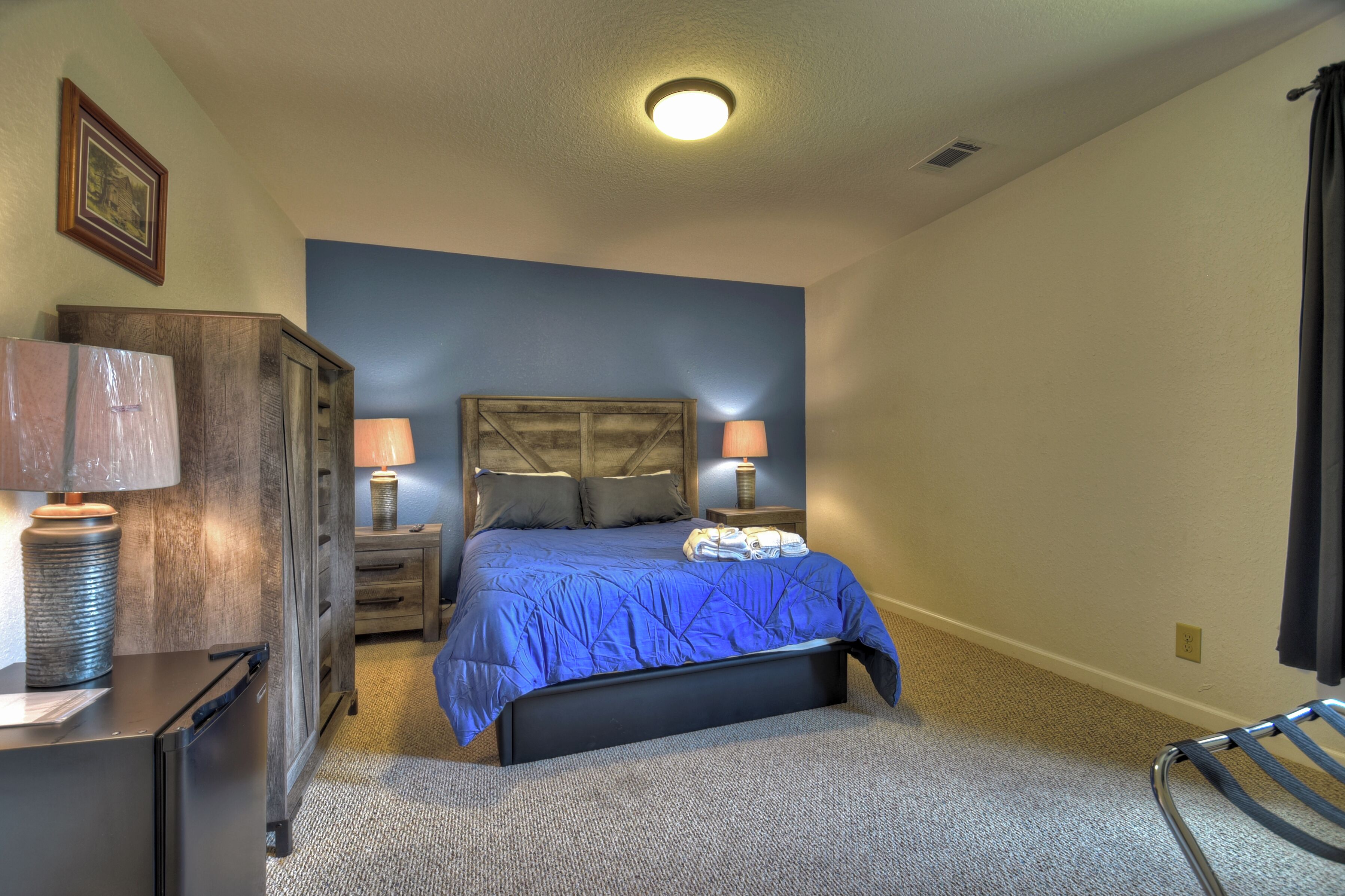 A bedroom with a bed, two bedside lamps, a dresser, and a chair.