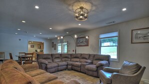 A spacious living room with a sectional sofa, a recliner, and a dining area with chairs and a table.