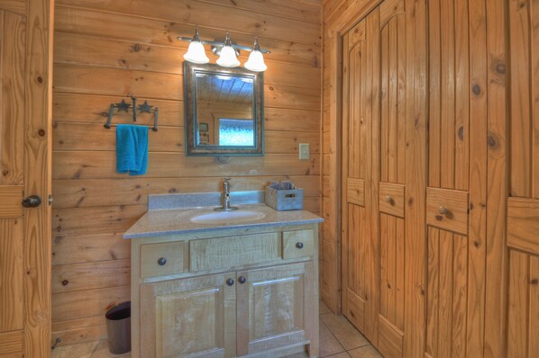 A wooden cabin bathroom with a sink, mirror, and three light fixtures above it.