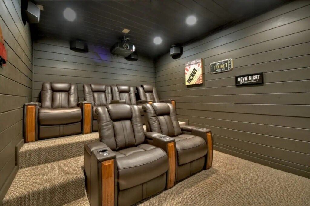 A home theater room with leather recliners, a carpeted floor, and a popcorn machine.