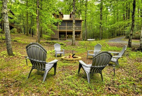 A cabin surrounded by a forest with outdoor seating and a fire pit. - Mountain Lake Delight- Pet Friendly | Hot Tub (Blue Ridge)