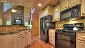 A kitchen with wooden cabinets, a refrigerator, a microwave, and an oven.