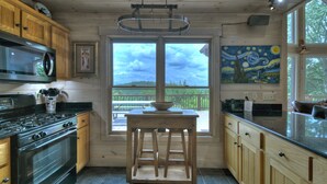 A kitchen with wooden cabinets, a stove, and a window with a view of the outdoors. - Champagne Chalet | MTN Views | Hot Tub | Secluded (Morganton)