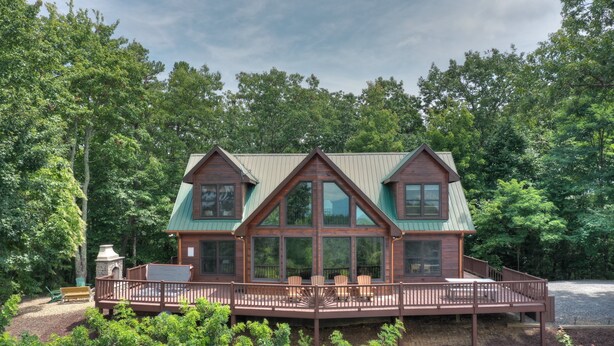 A cabin with a deck, large windows, and a green roof, surrounded by trees. - Champagne Chalet | MTN Views | Hot Tub | Secluded (Morganton)