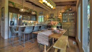 Cozinha espaçosa com ilha central, banquetas e mesa de jantar de madeira.