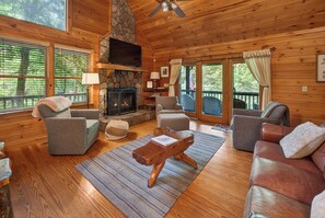 A cozy cabin interior with a stone fireplace, wooden walls, and a comfortable seating area.