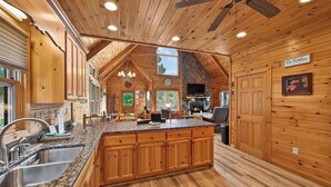 A spacious kitchen with wooden cabinets, granite countertops, and a stone fireplace. - Shepherd's Sky View | Secluded | MTN Views | Pool Table | (Morganton)
