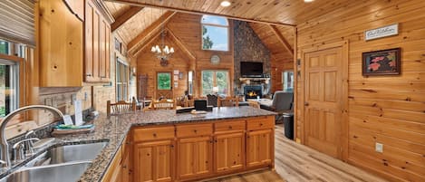 A spacious kitchen with wooden cabinets, granite countertops, and a stone fireplace.