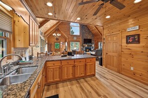 Une cuisine spacieuse dotée de meubles en bois, de plans de travail en granit et d’une cheminée en pierre.