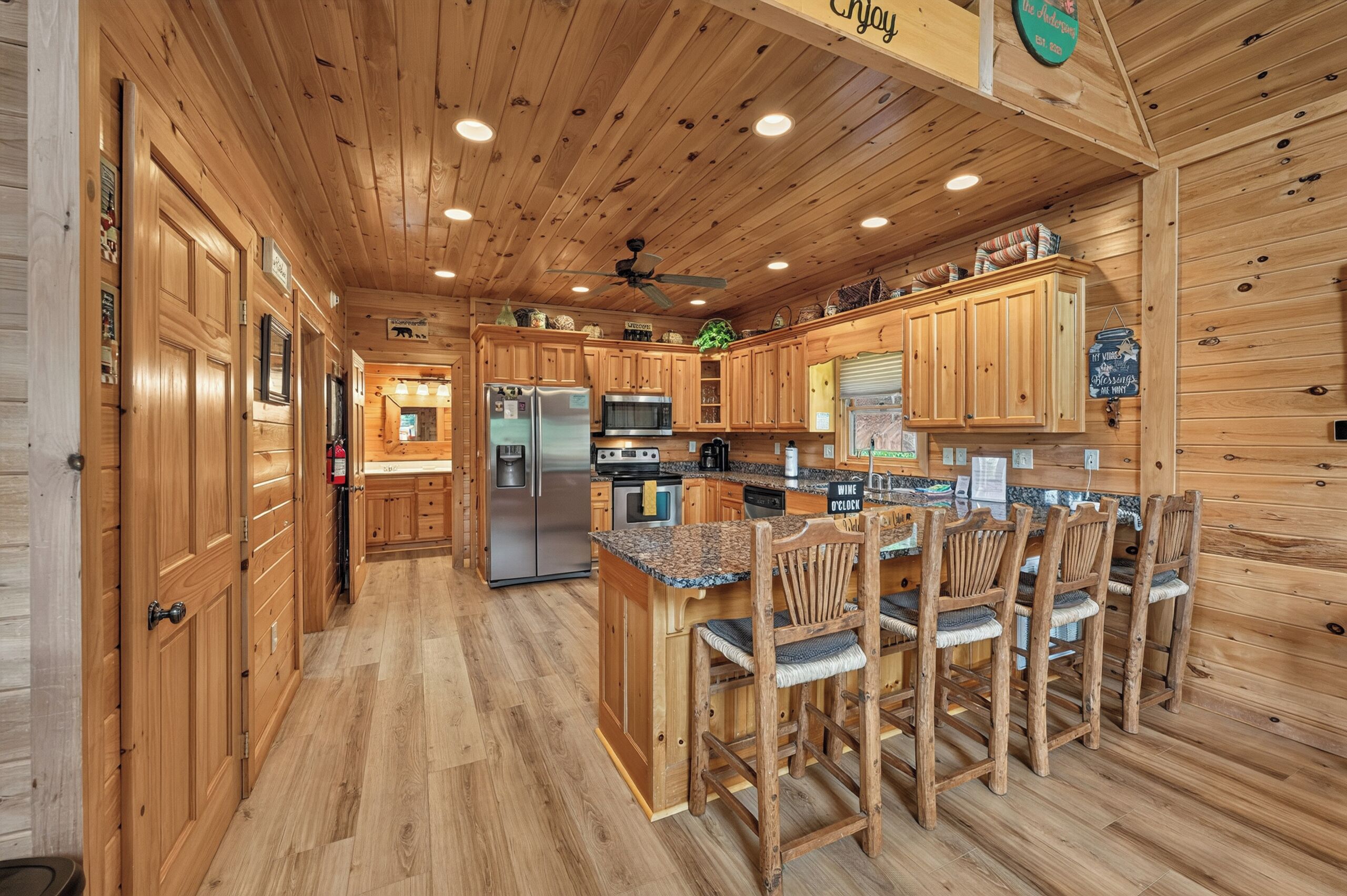 A wooden cabin interior with a kitchen area featuring a refrigerator, microwave, and wooden cabinets.