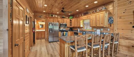 A wooden cabin interior with a kitchen area featuring a refrigerator, microwave, and wooden cabinets.