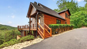 A two-story log cabin with a wooden deck and stairs leading to the entrance. - Shepherd's Sky View | Secluded | MTN Views | Pool Table | (Morganton)