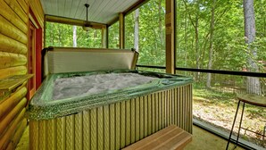 A hot tub in a cabin with a view of a forest.