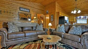 A cozy log cabin interior with a leather sofa set, a round coffee table, and a rustic wooden ceiling.