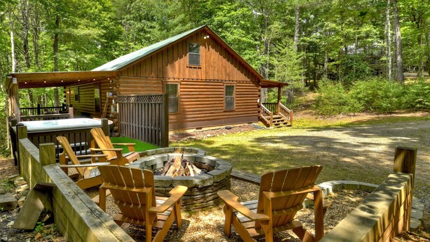 Une cabane avec un foyer et des fauteuils Adirondack dans la cour.