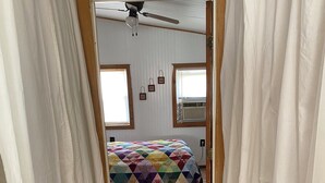 A bedroom with a bed, a ceiling fan, and a window with blinds.