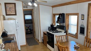 A compact kitchen with a stove, refrigerator, and dining area with wooden chairs and a table.