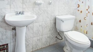 Ein Badezimmer mit einem Waschbecken auf Säule, Toilette und Spiegel.