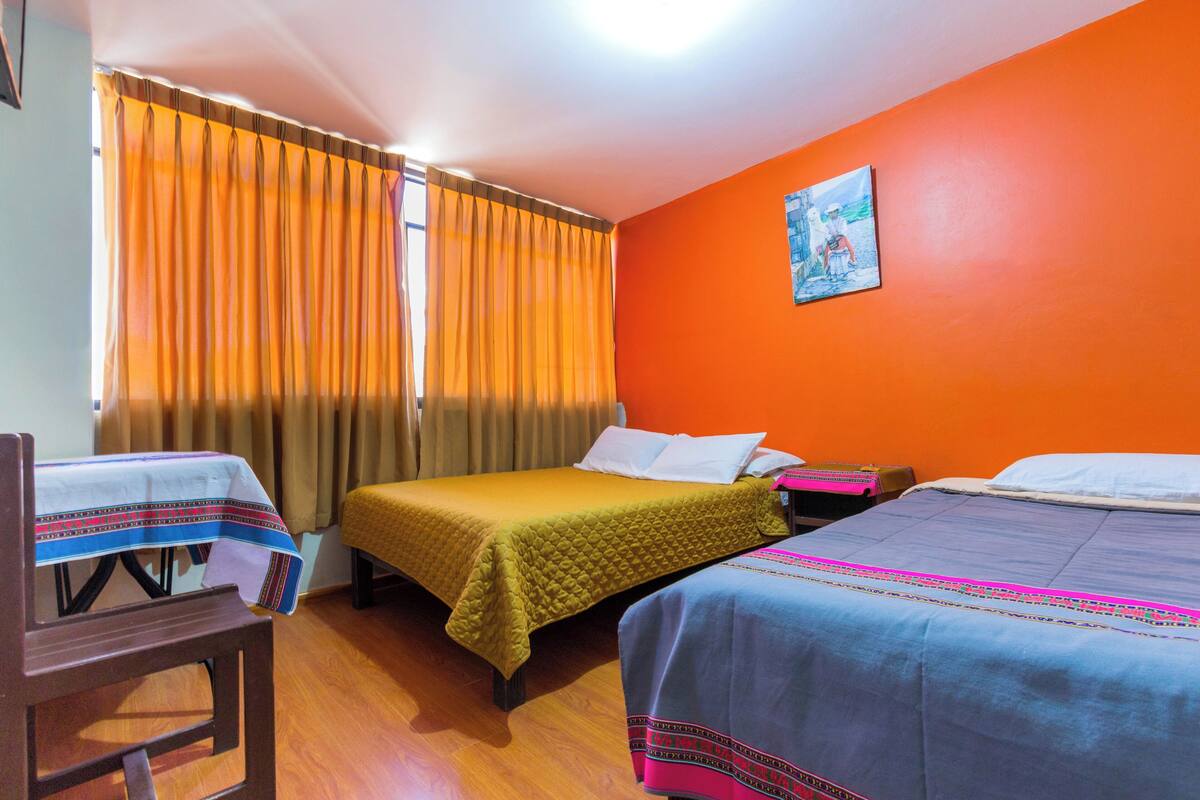 Quarto com duas camas, uma cadeira e uma mesa com toalha.