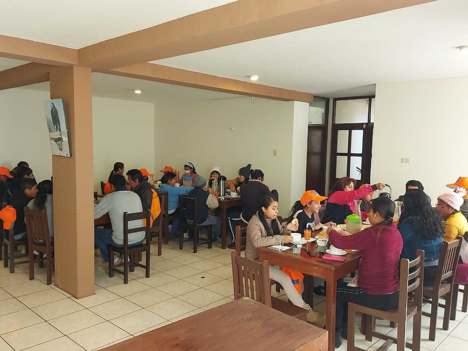 Uma área de refeições com várias mesas e cadeiras, pessoas sentadas e comendo.