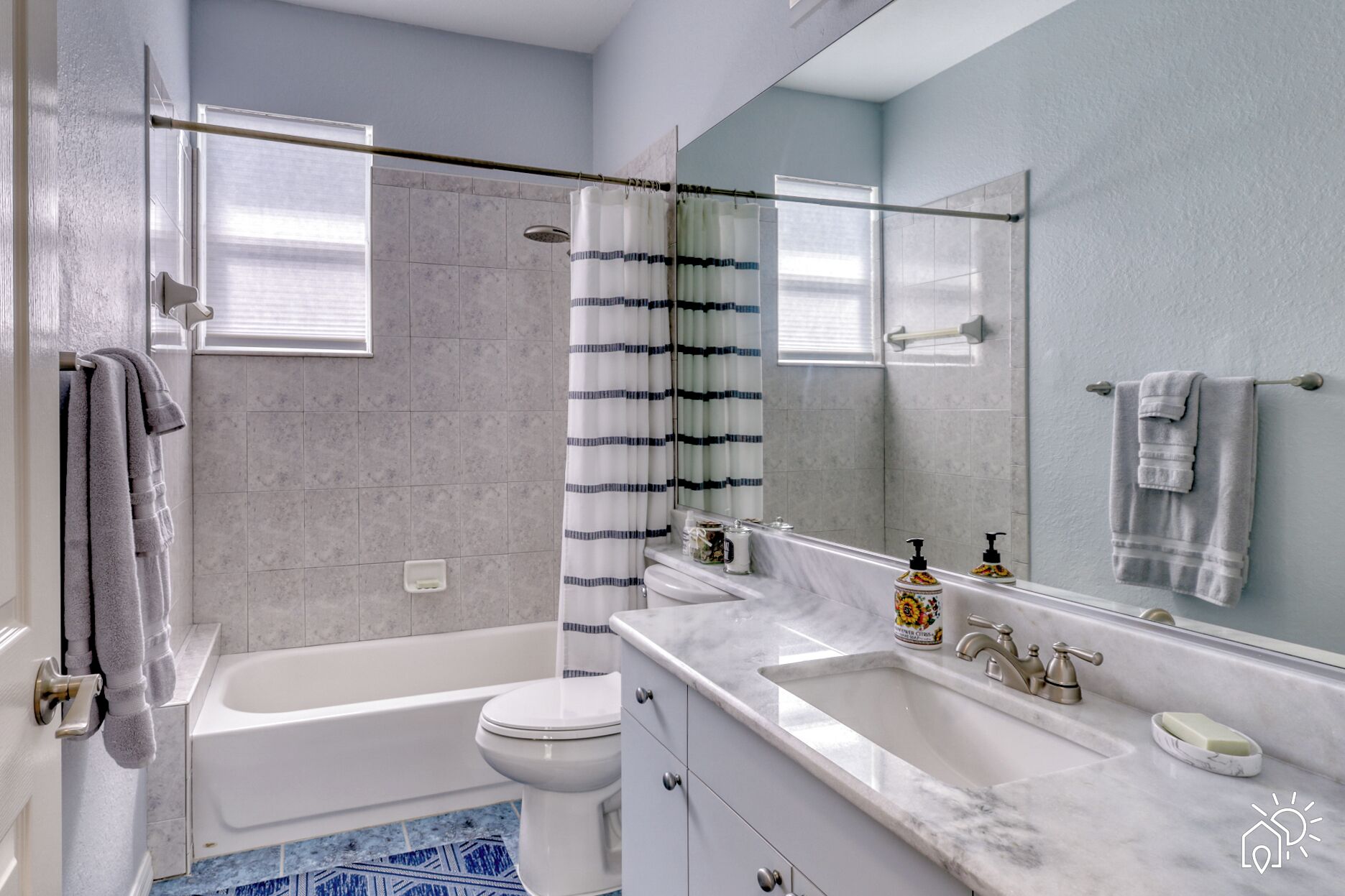 Un baño moderno con bañera, inodoro y un espejo grande.