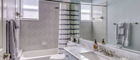 Un baño moderno con bañera, inodoro y un espejo grande.