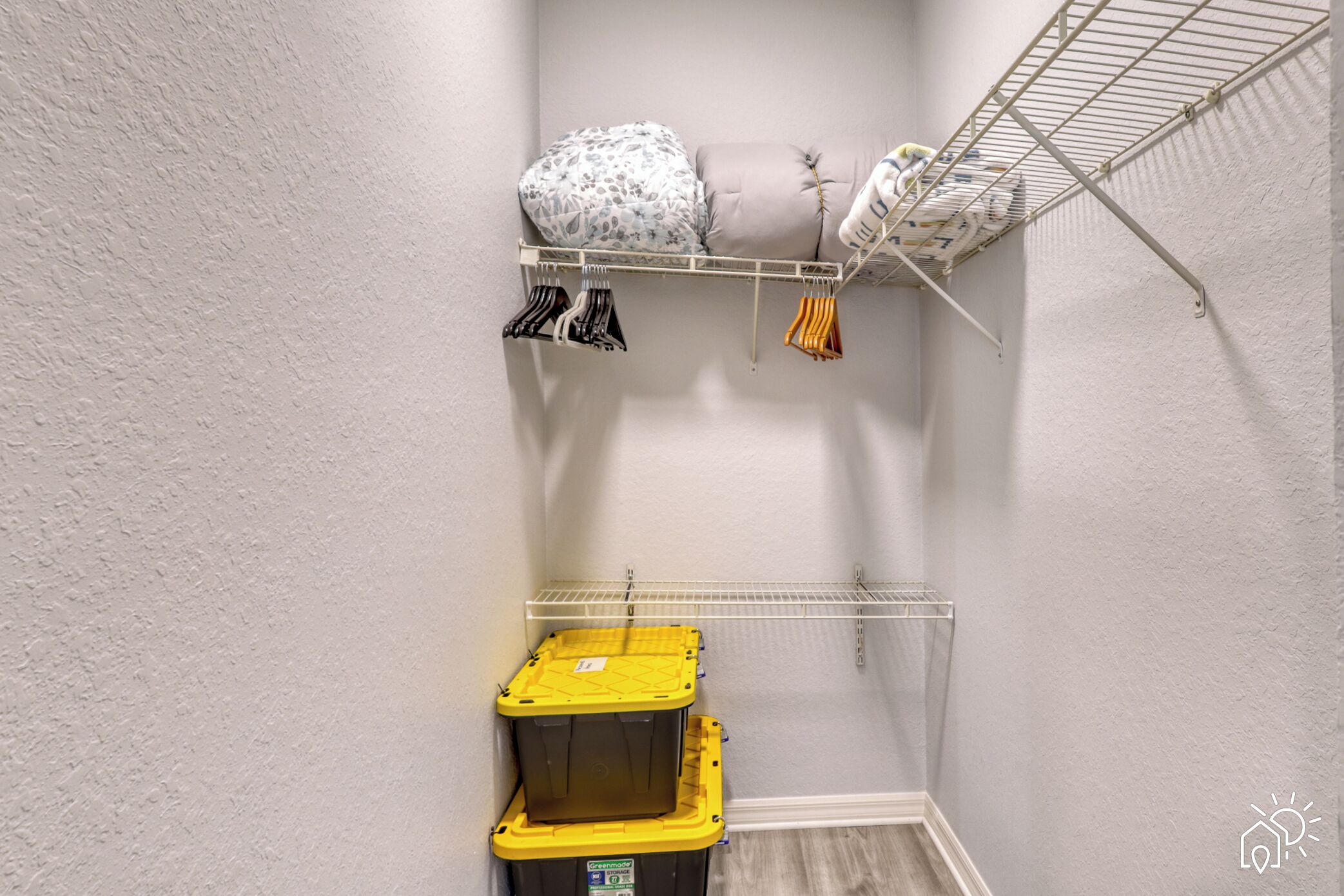 Un placard de rangement avec des étagères, une tringle pour suspendre les vêtements et deux bacs de rangement.