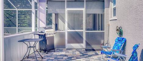 Un patio con una parrilla, mobiliario exterior y vista de la casa.