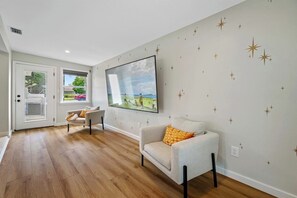 Un salon moderne avec un téléviseur à écran plat fixé au mur, deux canapés et un plancher en bois.