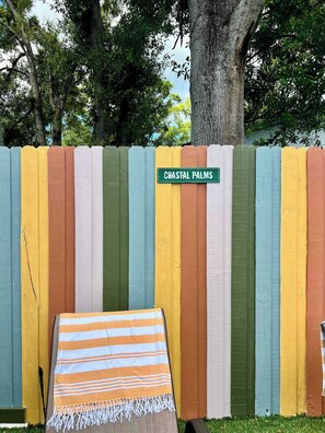 Een kleurrijk hek met een bord waarop staat 'COASTAL PALMS'.